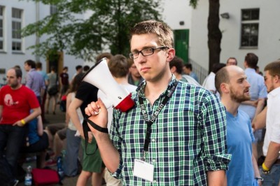 Public Speaking Champion Florian Umscheid mit finsterer Miene und der Siegertrophäe, dem Megaphon (c) Matthias Carcasona