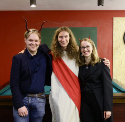 Drei Menschen, die als Teufel, Jesus und Teufel verkleidet sind.
